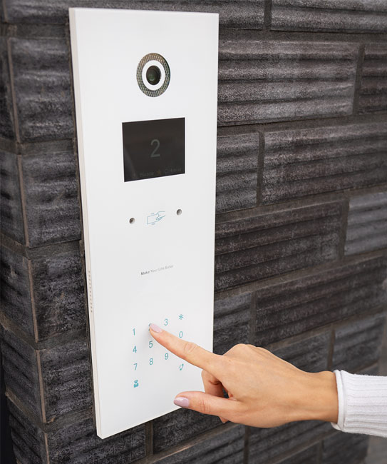 A person pressing a button on an apartment building's access control system.